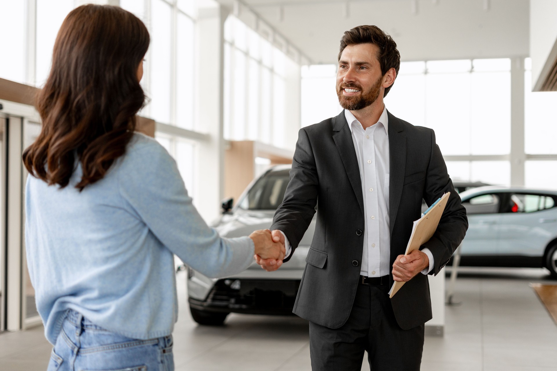 Car salesman shaking hands with customer in a dealership